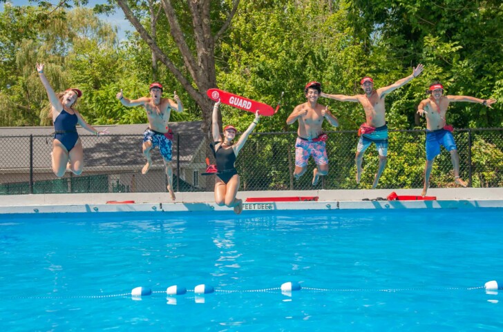 A group of Summer Trails staff jumping into a pool.